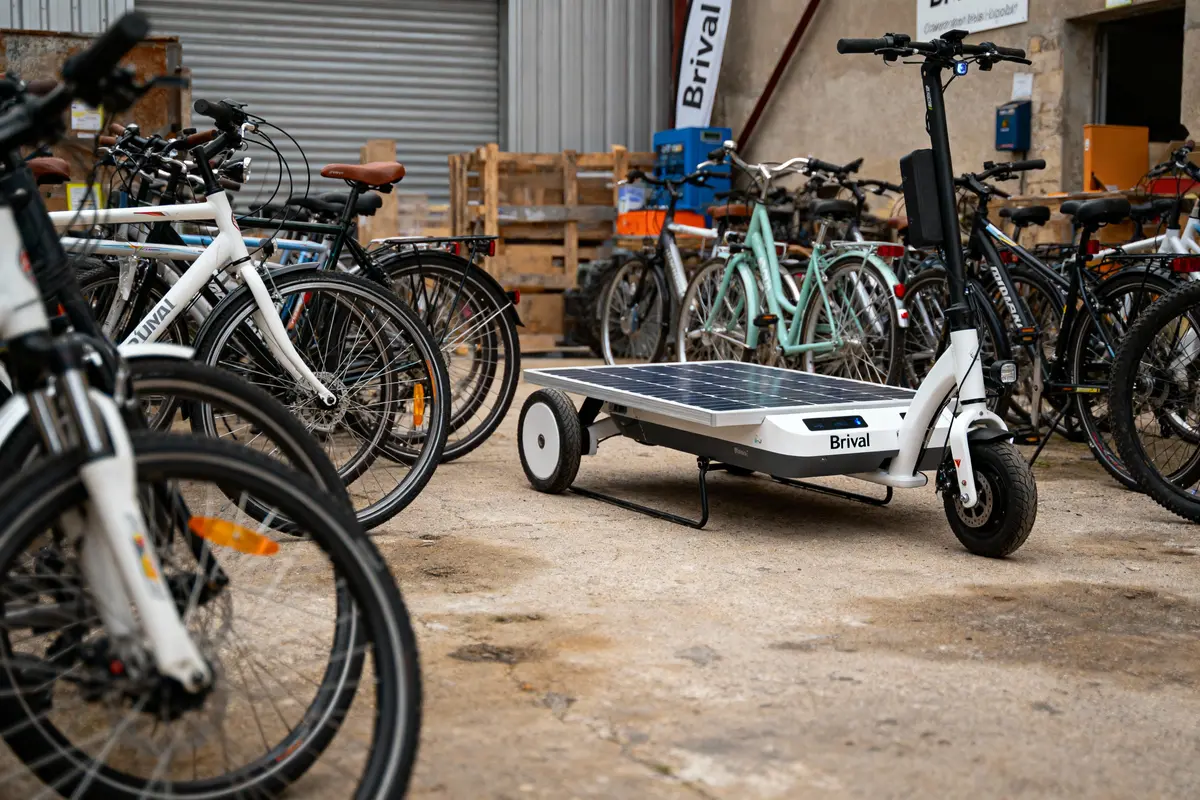 Trottinette avec panneau solaire au milieu de vélos dans un entrepôt.