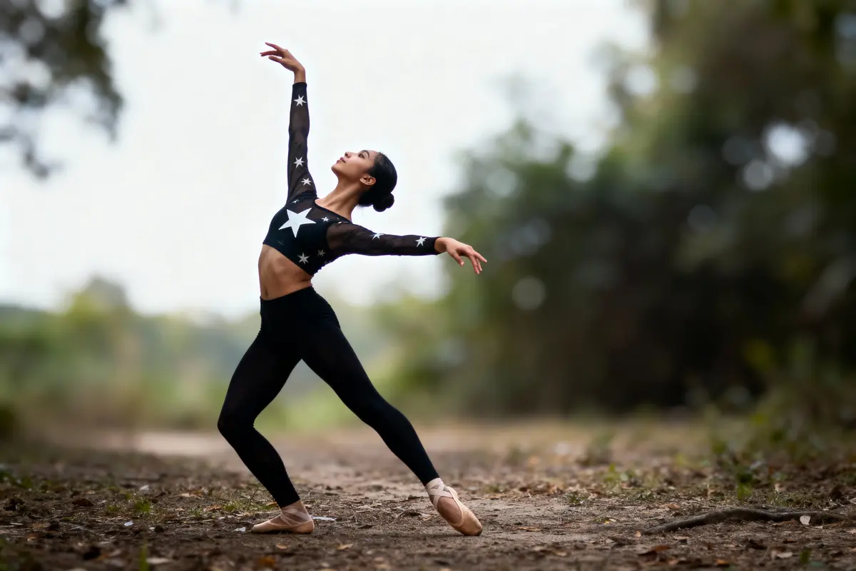 Danseuse en tenue étoilée effectuant une pose de ballet sur un chemin forestier flou en arrière-plan.