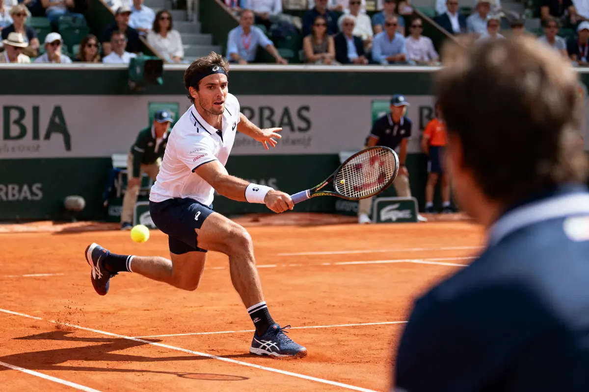Joueur de tennis en action sur court en terre battue, public en arrière-plan.