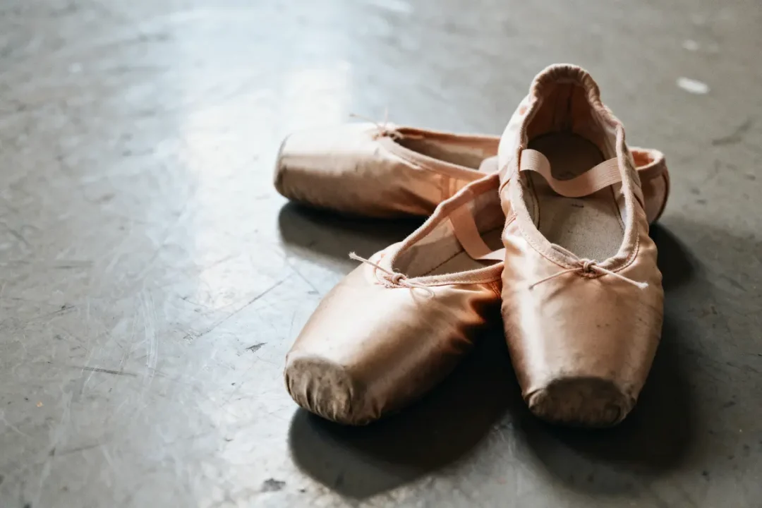 Paires de chaussons de danse rose sur un sol gris, en studio de danse.
