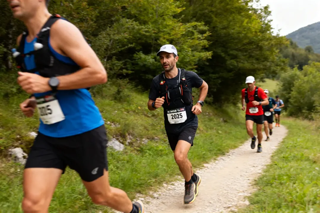 Participants courant sur un sentier forestier pendant l'Aymon Trail 2025 en montagne