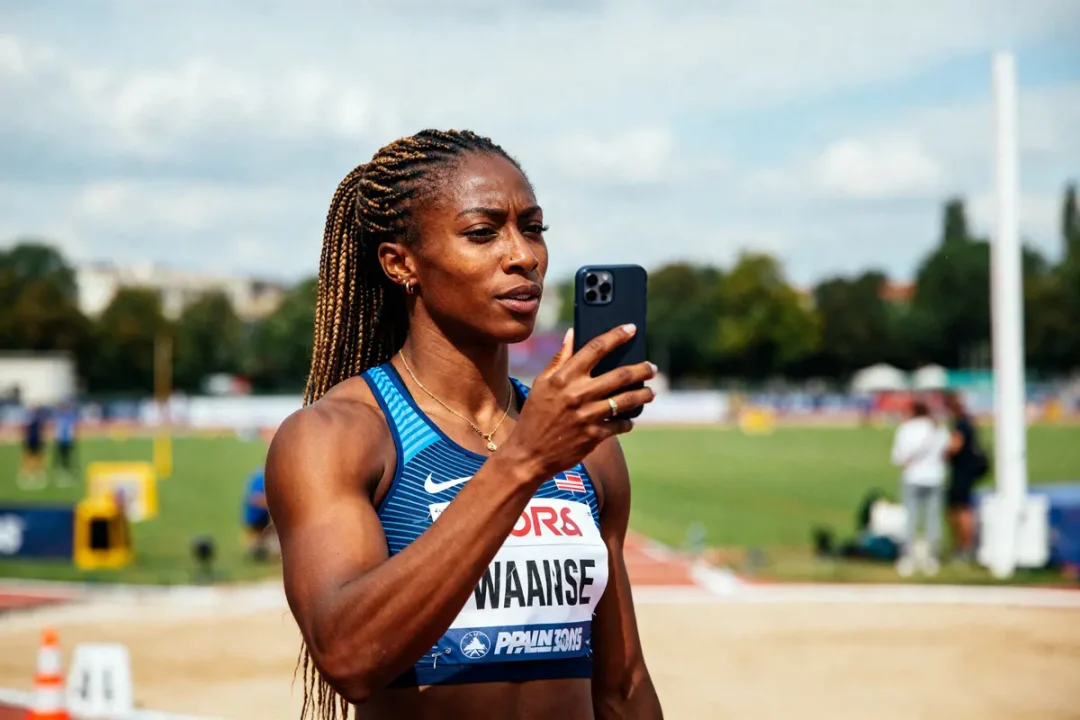 Athlète Maryse Éwanjé-Épée regardant son téléphone sur une piste d'athlétisme ensoleillée