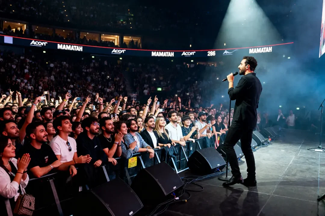Chanteur sur scène devant foule enthousiaste pendant concerts de Matmatah avec éclairage dynamique