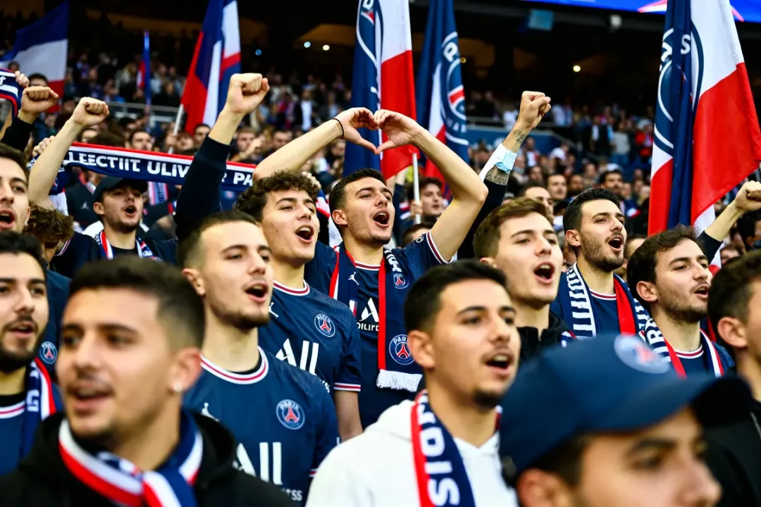 Des supporters du PSG chantent avec passion accompagnés de la musique du PSG dans le stade