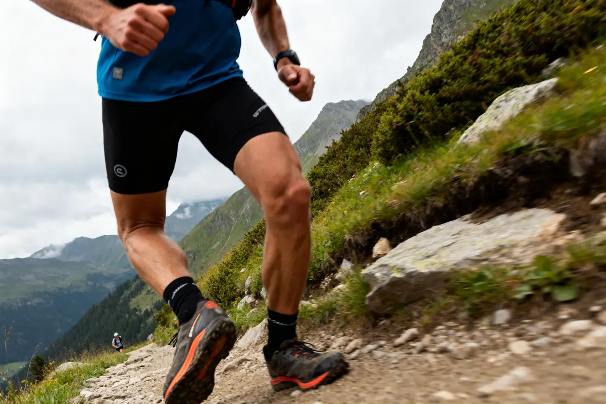 Coureur UTMB index sur sentier montagneux en pleine course Ă travers les Alpes