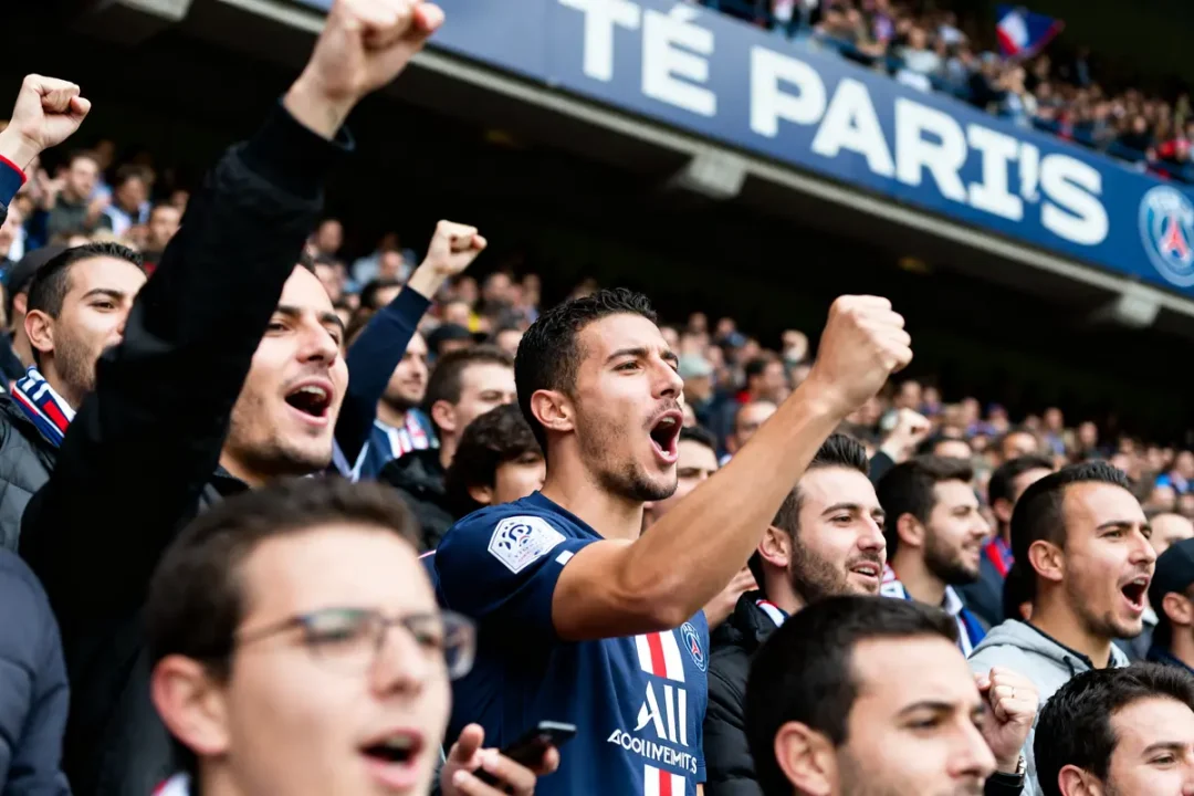 Supporters du PSG chantant avec ferveur au stade en soutien au Paris Saint-Germain