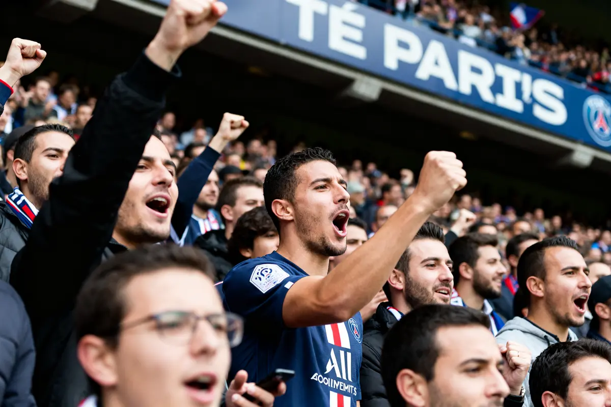 Supporters du PSG chantant avec ferveur au stade en soutien au Paris Saint-Germain