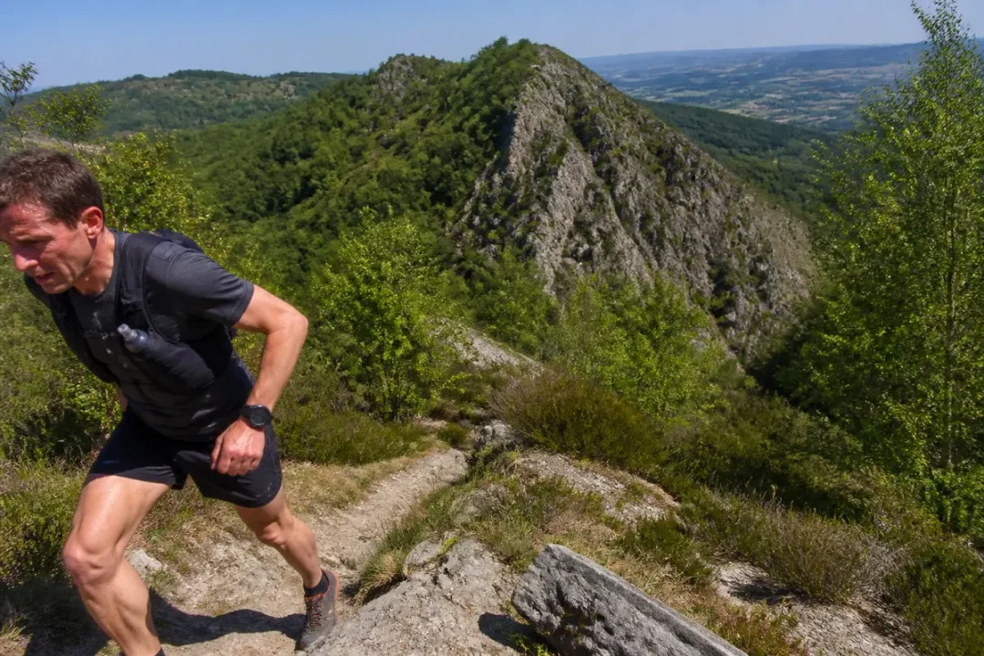 Coureur en montagne forestière sur un sentier escarpé pendant un trail running UTHA